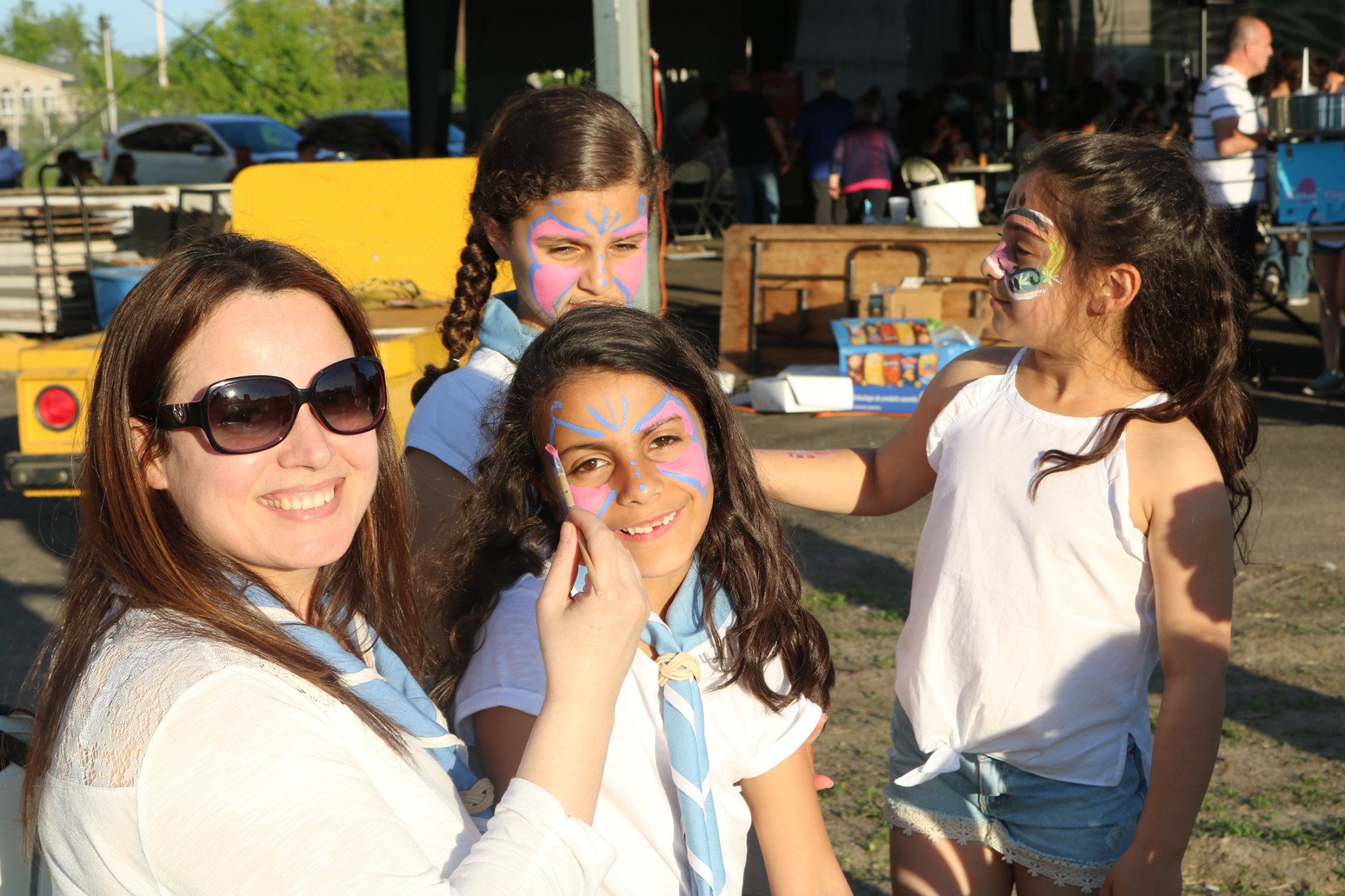 Leaders painting faces of smiling children at a parish festival